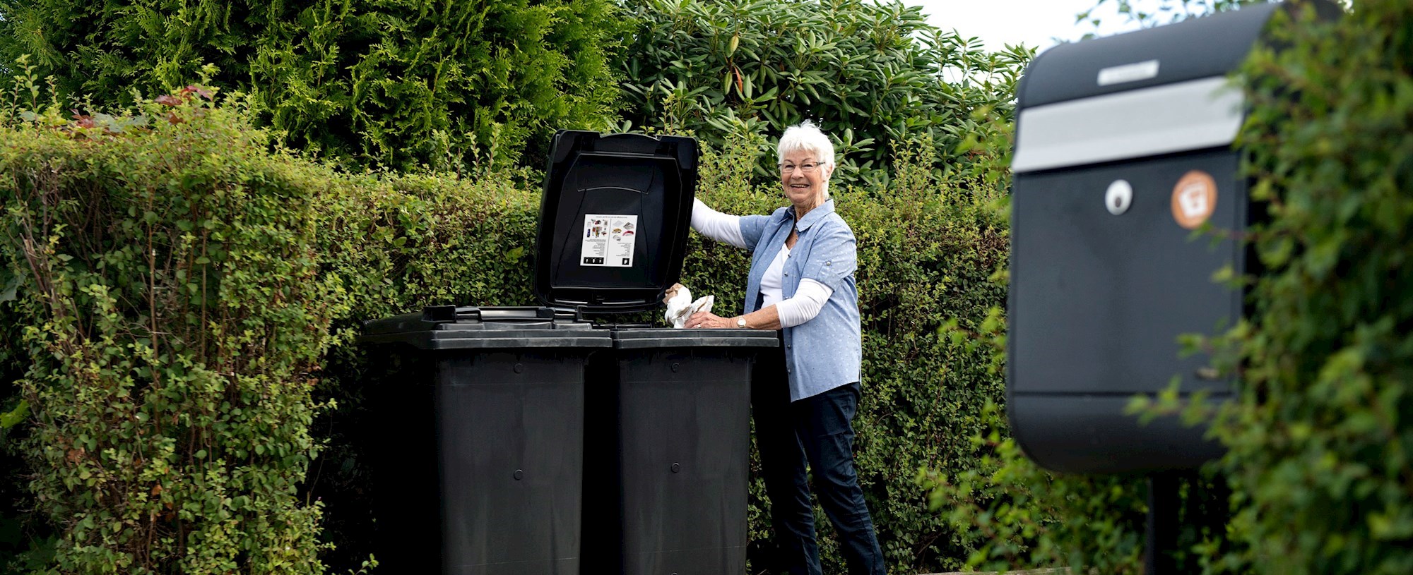 Dame sorterer affald ved containere